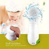 A white electric facial cleansing brush with soft bristles is shown next to a person using it for skincare.