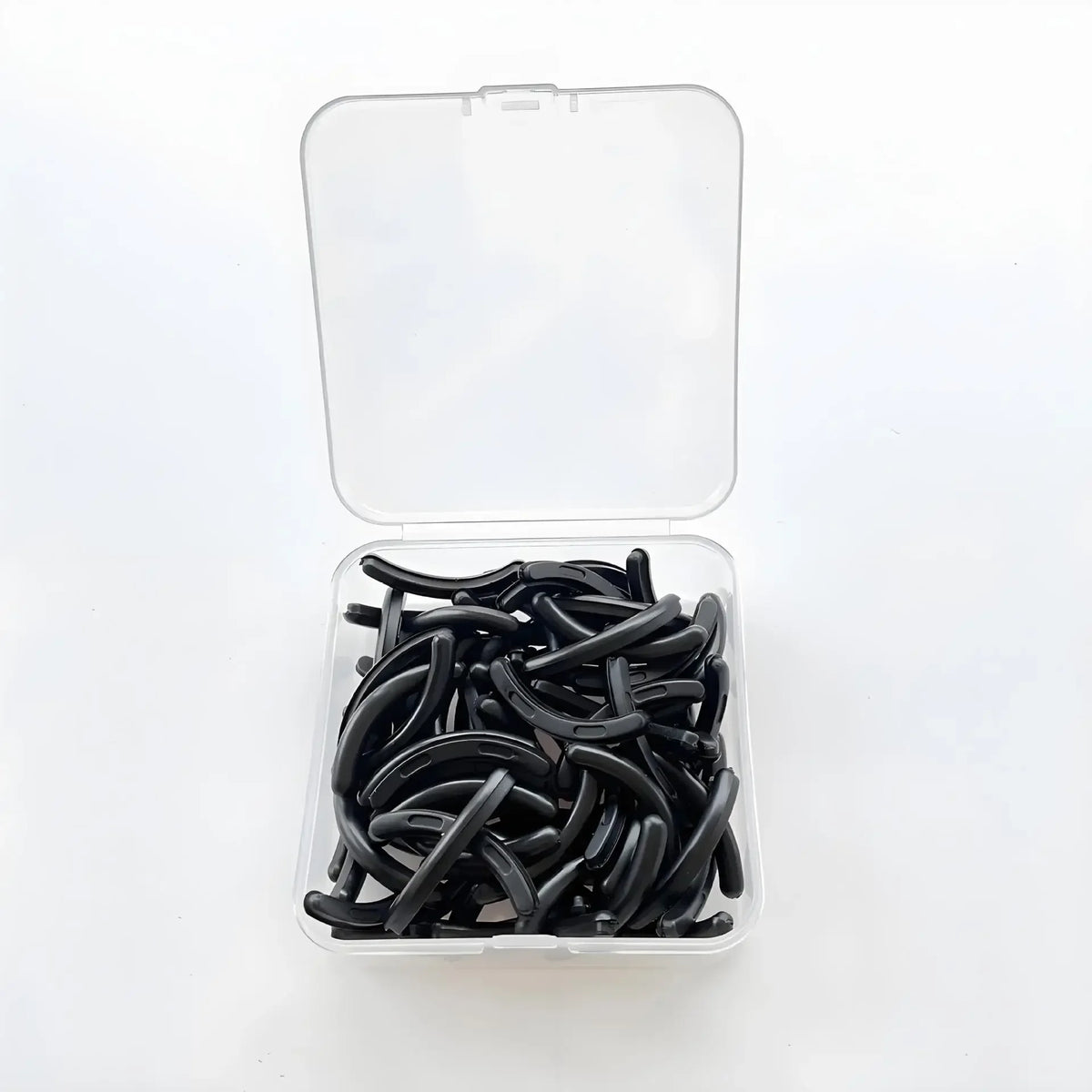 A clear plastic container holds thirty black reusable silicone eyelash curler pads.