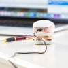 Depiladora eléctrica multi-cabeza blanca y oro rosa sobre una superficie blanca.