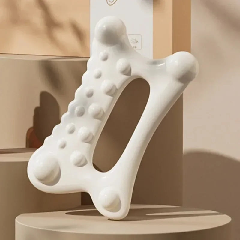 A white resin facial gua sha massage tool is displayed on a light-colored surface.
