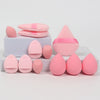 A set of twelve pink makeup sponges in various shapes and sizes arranged on a white surface.