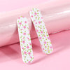 A set of double-sided nail files and buffing blocks with a pink floral pattern resting on a pink surface.