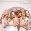 Five women smiling while holding a glass of rosé wine in front of a clock with Roman numerals