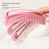 A hand holds a pink massage detangler hair brush designed for scalp massage.