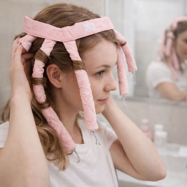 Eine Frau benutzt rosa, wiederverwendbare, hitzefreie Lockenstab-Styling-Stäbchen für die Nachtpflege ihrer Haare.