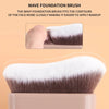 A close-up view of a wave foundation brush with brown and white bristles resting on a light-colored surface.