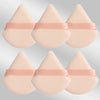 Un set de six éponges de maquillage triangulaires roses avec des élastiques roses.