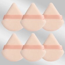 A set of six pink triangular makeup puffs with pink elastic bands.