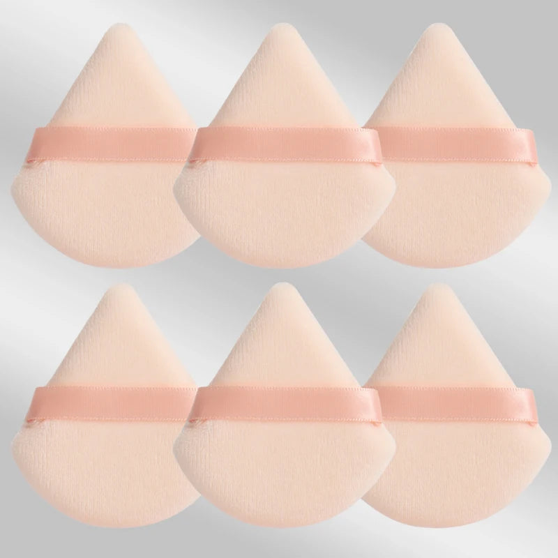Un set de six éponges de maquillage triangulaires roses avec des élastiques roses.