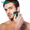 A man is using a black and teal electric hair trimmer on his ear.