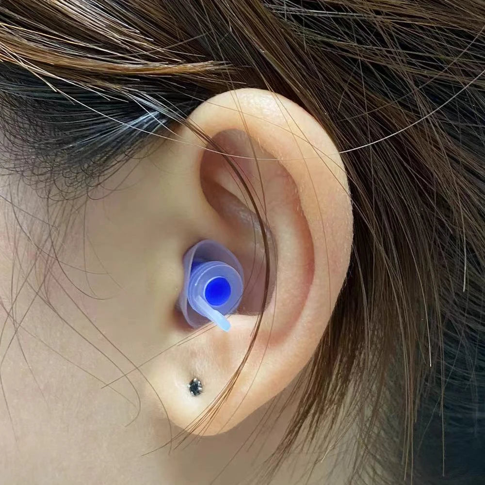 Primer plano de la oreja de una persona mostrando un tapón de silicona azul insertado en el canal auditivo.