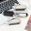 Silver folding mini hair comb with a mirror and bow resting on a white surface.