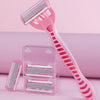 A pink 12-blade safety razor and replacement blades are displayed on a light pink surface.