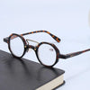 Une paire de lunettes rondes écaille de tortue posée sur un livre sombre.