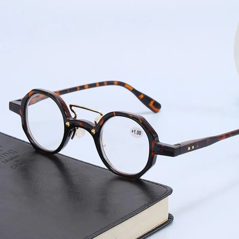 Une paire de lunettes rondes écaille de tortue posée sur un livre sombre.