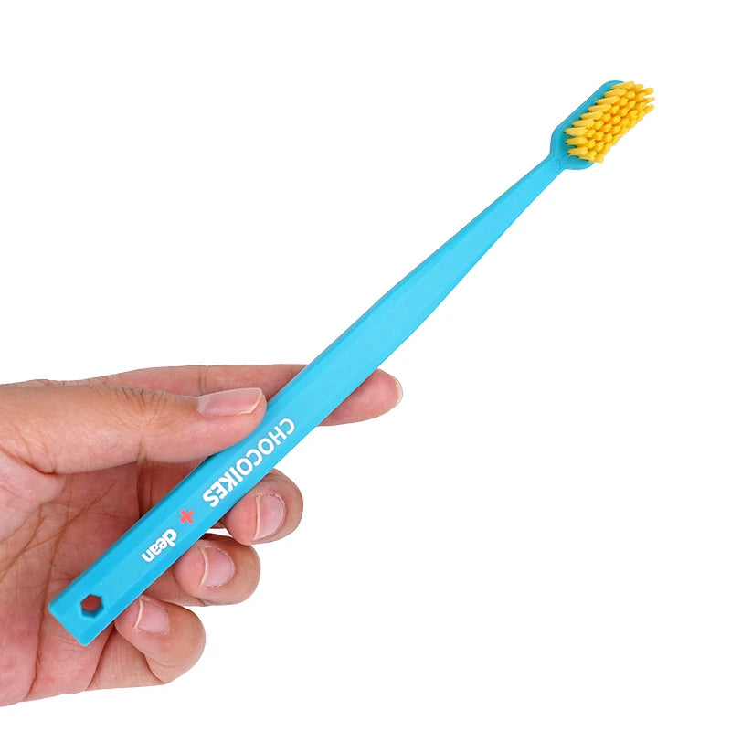 Une main tient une brosse à dents orthodontique bleu clair avec des poils jaunes fins.