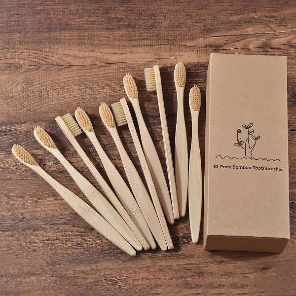 Une boîte contenant dix brosses à dents en bambou posées sur une surface en bois.