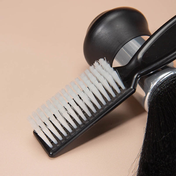 A black professional hair styling and cleaning brush set with a white bristles is shown against a light background.