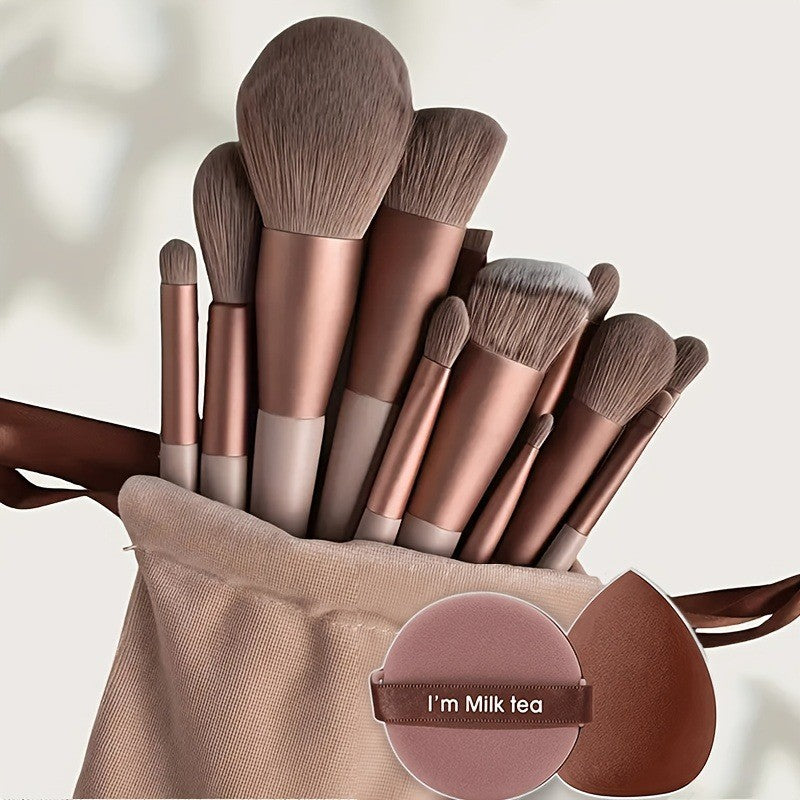A set of professional makeup brushes in rose gold and nude tones displayed in a beige pouch.